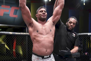 UFC拳手在八角籠內高舉雙臂慶祝勝利。 — 運動 壁紙