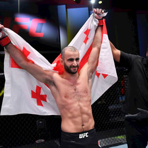 UFC拳手在八角籠內手持喬治亞國旗慶祝勝利。 — 終極格鬥冠軍賽 壁紙