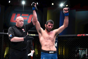 UFC拳手在八角籠中高舉雙臂慶祝勝利。 — 終極格鬥冠軍賽 壁紙