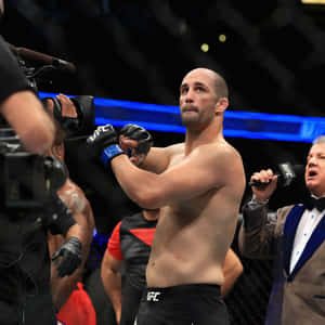 UFC拳手在八角籠內舉起雙臂慶祝勝利。 — 終極格鬥冠軍賽 壁紙