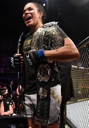 UFC拳手在八角籠內手持冠軍腰帶慶祝勝利。 — 慶祝 壁紙