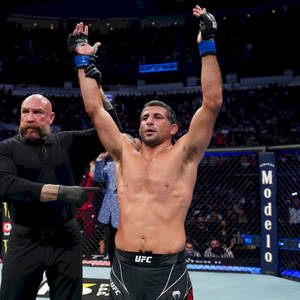UFC拳手在八角籠內高舉雙臂慶祝勝利。 — 終極格鬥冠軍賽 壁紙