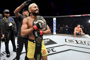 UFC拳手在八角籠中獲勝後手持冠軍腰帶 — 運動 壁紙