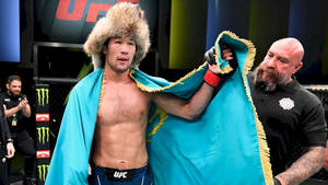 UFC拳手在八角籠中獲勝後披著國旗戴著毛帽。 — 運動 壁紙