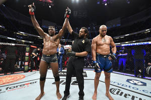 UFC拳手在八角籠內與裁判慶祝勝利。 — 運動 壁紙