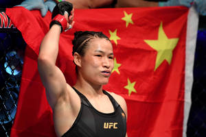 女性MMA拳手在UFC八角籠內手持中國國旗慶祝勝利。 — 運動 壁紙
