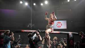 女性MMA拳手在攝影師包圍下跳上籠邊圍欄慶祝勝利。 — 終極格鬥冠軍賽 壁紙