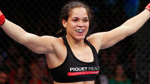 女性MMA拳手在八角籠中舉起雙臂慶祝勝利。 — 勝利 壁紙