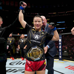 UFC拳手在八角籠中舉起冠軍腰帶慶祝勝利。 — 運動 壁紙