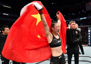 UFC拳手披著中國國旗在八角籠中慶祝勝利。 — 運動 壁紙