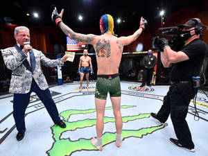MMA拳手在八角籠中高舉雙臂慶祝勝利。 — Monster Energy 壁紙