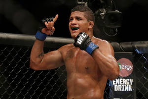 一位汗流浹背的MMA拳手在UFC八角籠內舉起手指慶祝勝利。 — 極限運動 壁紙