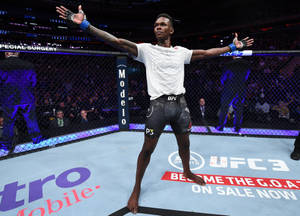UFC拳手在八角籠中高舉雙臂慶祝勝利。 — 以色列·阿德桑亞 壁紙