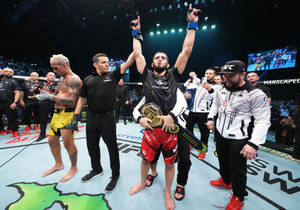 MMA拳手在八角籠中手持冠軍腰帶慶祝勝利。 — 慶祝 壁紙