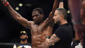 MMA拳手在八角籠內獲勝，裁判舉起他的手。 — 勝利 壁紙