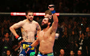 MMA拳手在八角籠內舉拳慶祝勝利。 — 終極格鬥冠軍賽 壁紙