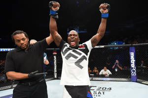 UFC拳手高舉雙臂慶祝勝利，裁判舉起他的手。 — 終極格鬥冠軍賽 壁紙