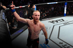 一位赤裸上身的MMA選手在UFC八角籠內高舉雙手慶祝勝利。 — 終極格鬥冠軍賽 壁紙
