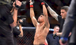 MMA 拳手在八角籠內高舉雙臂慶祝勝利。 — 終極格鬥冠軍賽 壁紙