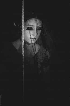 一位戴著面紗、化著深色妝容的女性，在黑白照片中透過繩索觀看。 — 黑夜 壁紙