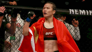 女MMA拳手披紅旗在UFC八角籠慶祝勝利。 — 運動 壁紙
