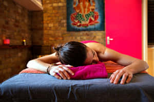 一位女士在一個有磚牆和蠟燭的水療中心的按摩床上安詳地睡覺。 — 放鬆 壁紙