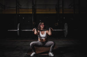 運動型女士在燈光昏暗的健身房中用槓鈴進行深蹲。 — 槓鈴 壁紙