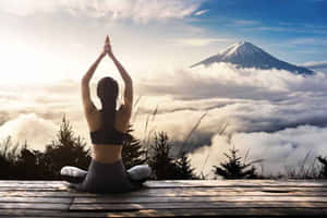 人在木製平台上以瑜伽姿勢冥想，下方有富士山和雲海。 — 山景 壁紙