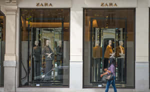 一位女士走過Zara商店櫥窗，櫥窗內有穿著西裝的人體模型。 — Zara 壁紙