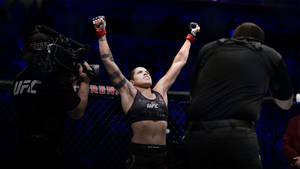 女性MMA拳手在UFC八角籠內高舉雙臂慶祝勝利。 — 終極格鬥冠軍賽 壁紙