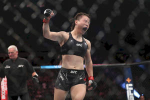 女性MMA拳手在UFC八角籠內高舉拳頭慶祝勝利。 — 運動 壁紙