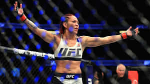 女性MMA拳手在UFC八角籠中高舉雙臂慶祝勝利。 — 終極格鬥冠軍賽 壁紙