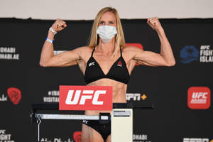 女性UFC拳手在稱重時戴著口罩展示手臂。 — 終極格鬥冠軍賽 壁紙