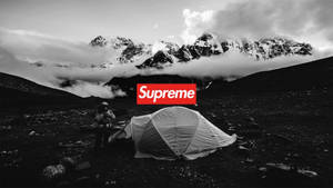 一位遠足者在山景中搭建帳篷，並疊加了一個紅色的Supreme標誌。 — 酷炫至尊 壁紙