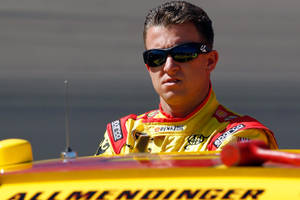 穿著賽車裝備的NASCAR車手從他的黃色賽車中探出身子。 — 極限運動 壁紙