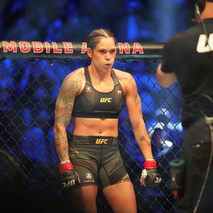 身穿UFC裝備的女MMA拳手在比賽期間站在八角籠內。 — 終極格鬥冠軍賽 壁紙