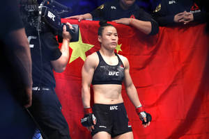 女性UFC拳手穿著黑色裝備站在帶有黃星的中國國旗前。 — 運動 壁紙