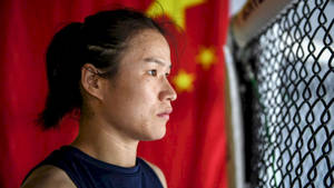 一位堅定的女戰士透過圍欄觀望，背景有中國國旗。 — 運動 壁紙