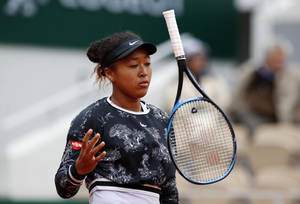 女網球選手在比賽中於紅土球場握著球拍。 — 羽球 壁紙