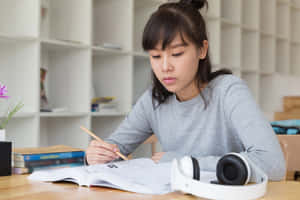 年輕女性在桌上學習，有耳機和筆記本 — 讀書 壁紙