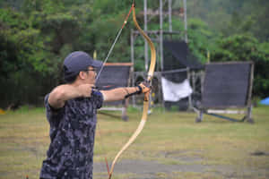 男子在戶外射箭場瞄準弓箭。 — 蝙蝠俠 壁紙