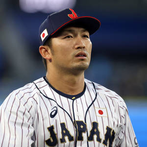 身穿制服的日本棒球運動員在夜間比賽中專注地凝視 — 日式 壁紙