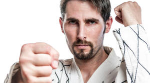 一名穿著武術制服的男人帶著堅定的表情向前出拳。 — 男人 壁紙