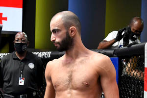 一位赤裸上身的MMA拳手在八角籠中，附近有戴口罩的工作人員。 — 運動 壁紙