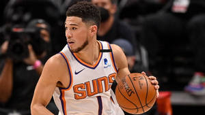 職業籃球運動員穿著Suns球衣在比賽中運球。 — Devin Booker 壁紙