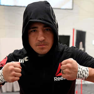 MMA拳手身穿黑色連帽衫和UFC護腕，在健身房中握拳擺姿勢。 — 運動 壁紙