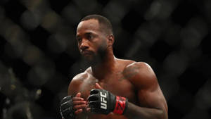 比賽期間，一位肌肉發達的MMA拳手戴著UFC手套站在八角籠內。 — 酷 壁紙