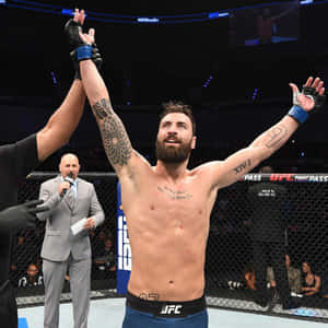 UFC拳手在八角籠中慶祝勝利，裁判舉起他的手。 — 運動 壁紙