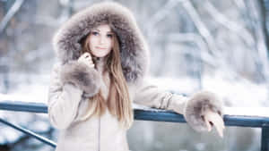 穿著冬季外套的女子在雪地森林中倚靠積雪欄杆 — 冬季美學 壁紙