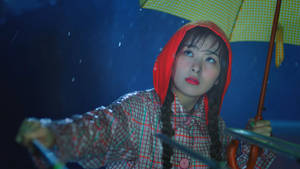 夜晚雨中，穿著紅色連帽雨衣的女子撐著黃色雨傘。 — 紅色天鵝絨 壁紙